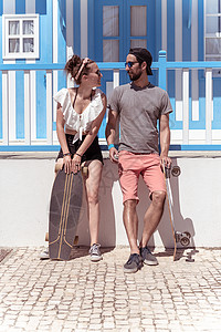 科斯塔诺瓦在葡萄牙阿维罗Aveiro典型的科斯塔新屋附近玩滑板的年轻活跃夫妇背景