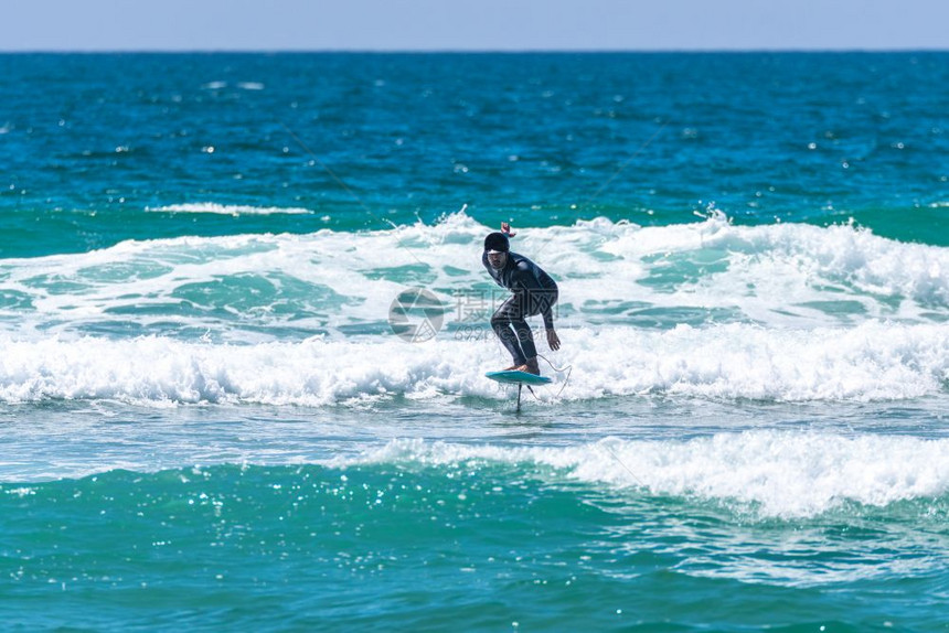 一个中年男子在阳光明媚的白天在海中冲浪或流油图片