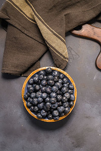 新鲜蓝莓陶瓷碗和棕色布在黑桌生锈风格图片