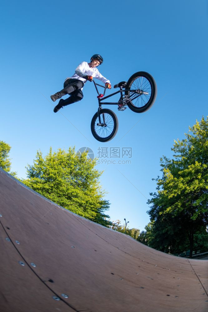 Bmx特技表演在滑板场的迷你坡道顶部图片