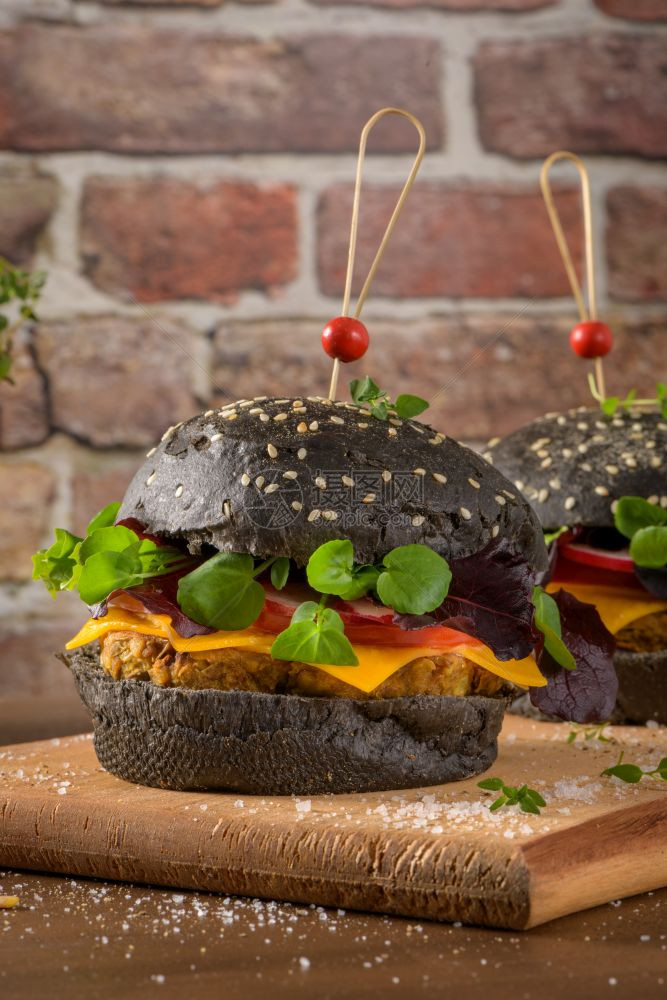 美味的烤肉汉堡扁豆干西红柿和百草枯黑面包在木制顶上图片