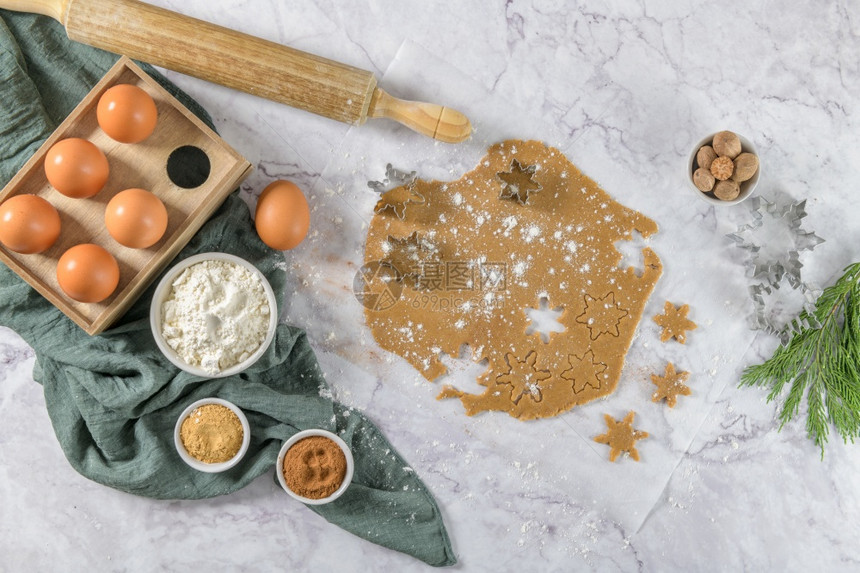 大理石厨房柜台上的圣诞饼干和剪刀的原始面粉图片