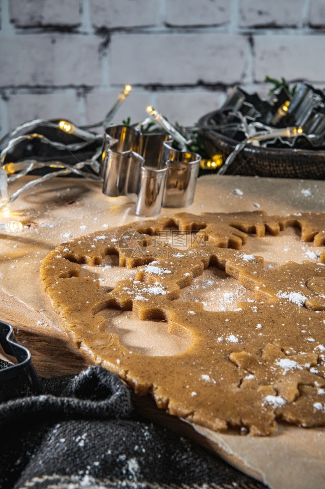圣诞饼干和剪刀的原始面粉在木制的黑暗厨房柜台图片