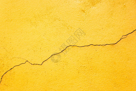 黄色旧墙壁中间的简单裂缝图片