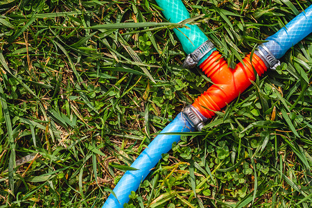 绿色草地上的蓝红塑料水管断裂器图片