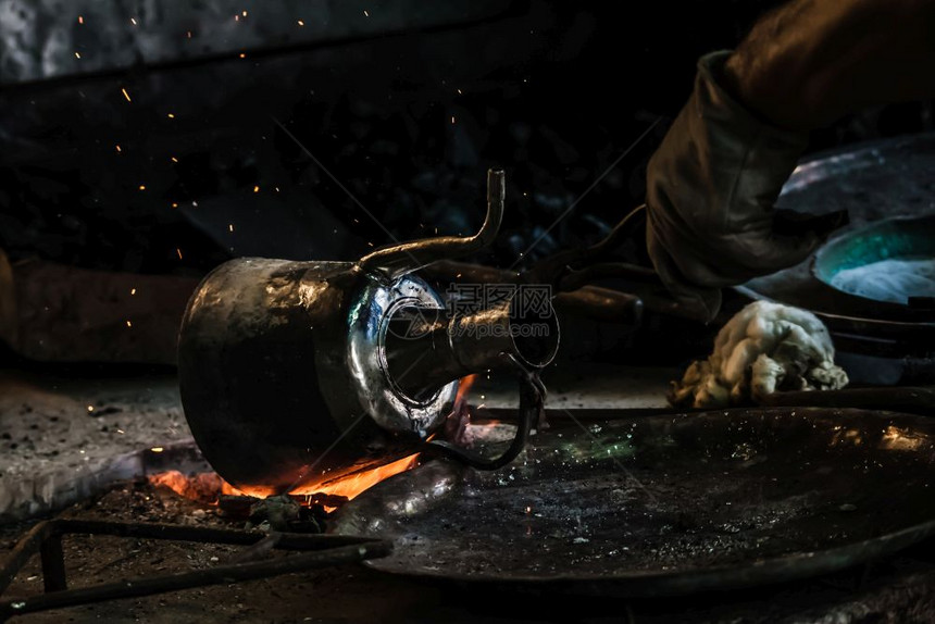 土耳其传统铁匠用火上喷洒的锡覆盖铜质物体图片