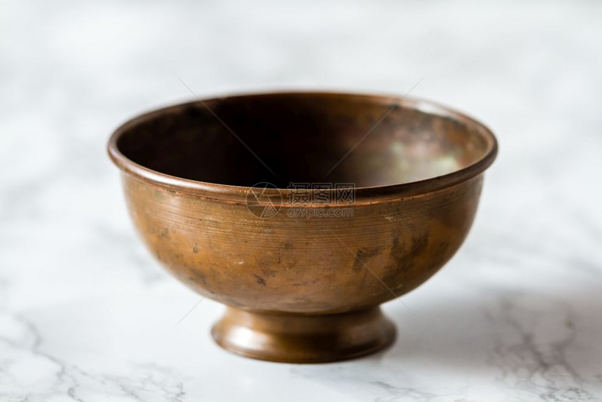 大理石背景上真实的手工土制铜碗图片