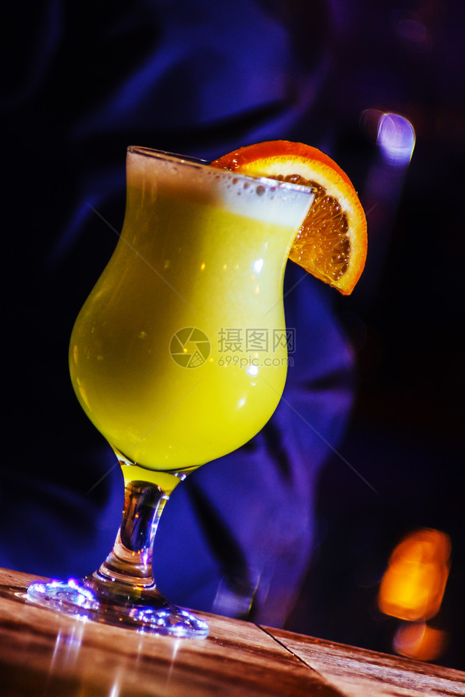 一个美丽的黄色鸡尾酒里面有白泡沫和橙色切片在高玻璃杯里图片