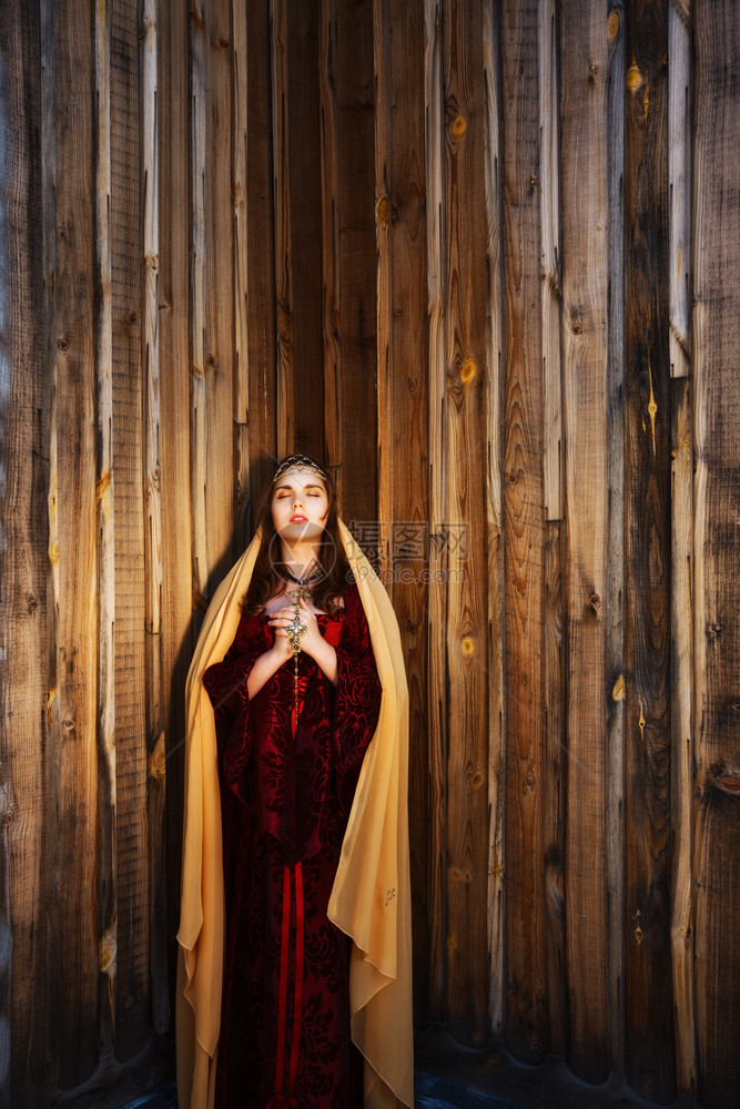 迷人的棕色头发女在木墙附近祈祷图片