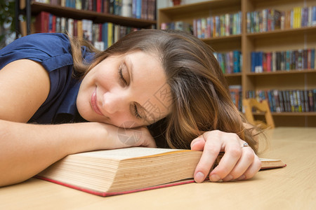 女孩躺在图书馆的一本上闭眼睛笑着微图片