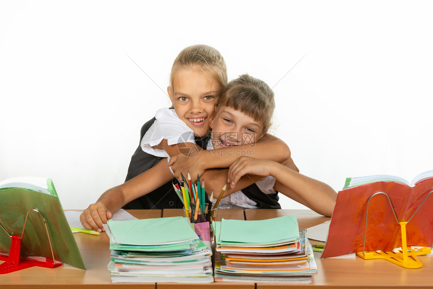 两位女学生坐在书桌旁看教科图片