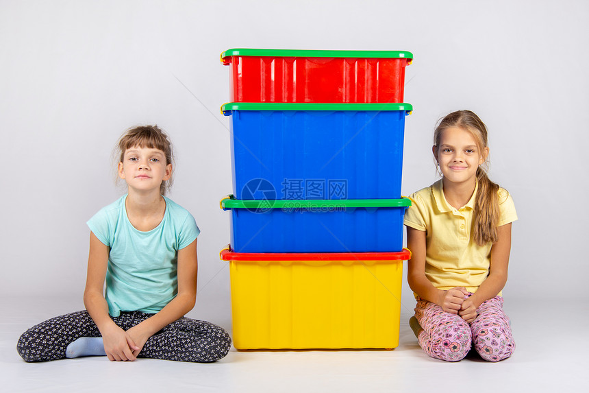 两个女孩坐在四大塑料箱旁边图片