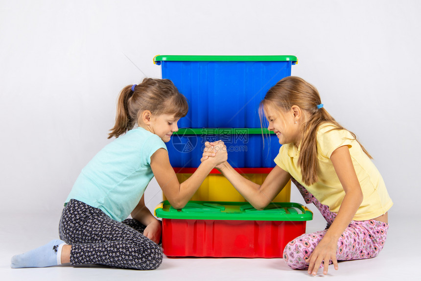 两个女孩亲手打架把肘放在一个装玩具的盒子上图片