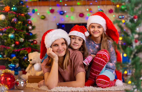 妈和两个女儿躺在一棵圣诞树的地板上图片