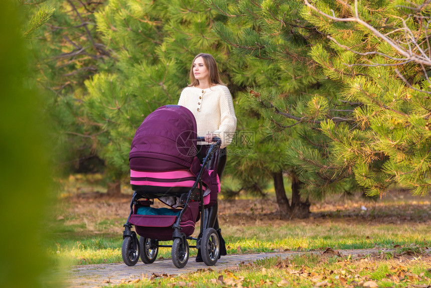 妈和新生儿一起在秋天城市公园散步图片