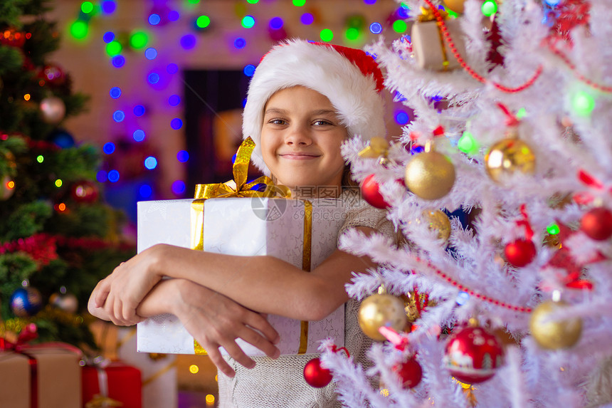 在白圣诞树上送礼物的快乐美女图片