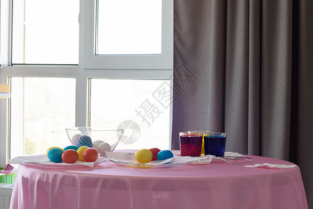 房间窗边内装有彩色鸡蛋和染色剂的桌子图片