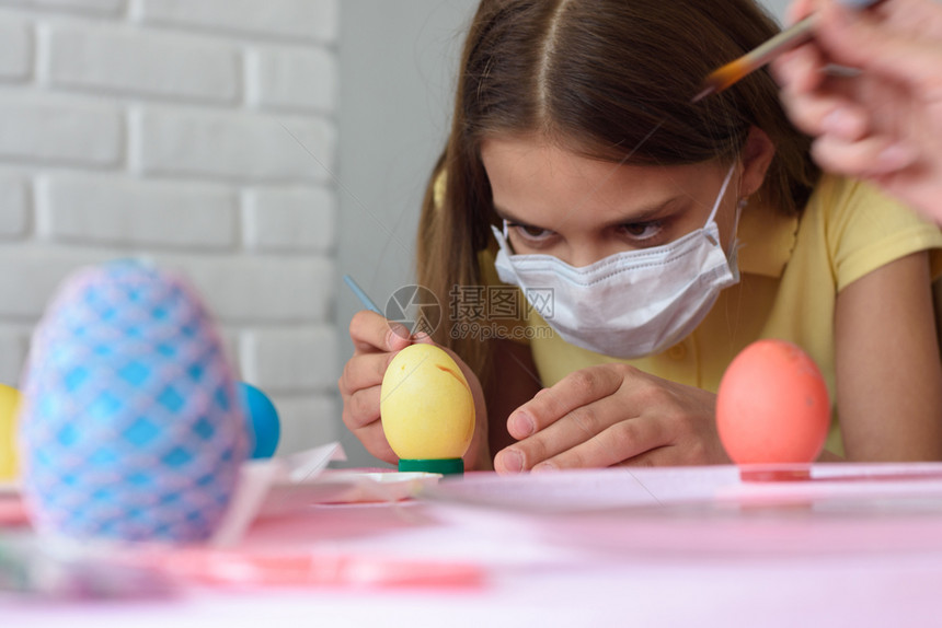 一名身戴医疗面具画复活节鸡蛋的女童肖像图片