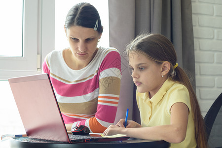 母亲和女儿用在线远程学习解决家庭作业图片