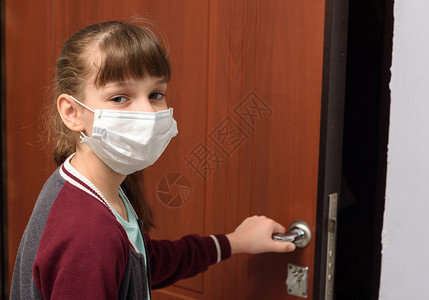 戴医疗保护面罩的女孩打开公寓门图片