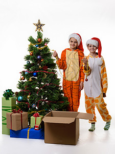 两个女孩站在圣诞树旁边手里握着喜悦的罐子图片