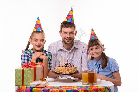 爸和两个女儿在餐桌上有个节日蛋糕的愉快地看框架图片