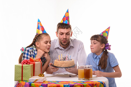 父亲和两个女儿在生日蛋糕上吹蜡烛图片