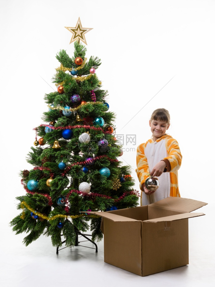 女孩检查圣诞装饰品把它们从圣诞树上拉出来图片