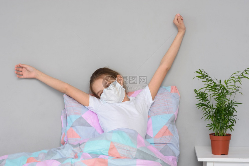 一名身戴医疗面具的正在康复女孩早上醒来在床摇欲休图片