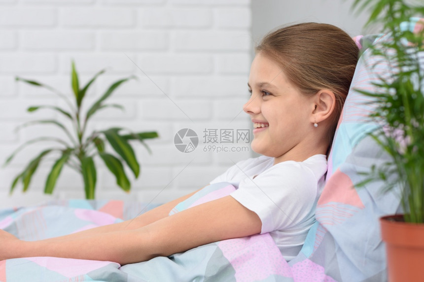 早晨快乐的十岁女孩躺在床上微笑图片