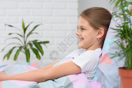 早晨快乐的十岁女孩躺在床上微笑图片