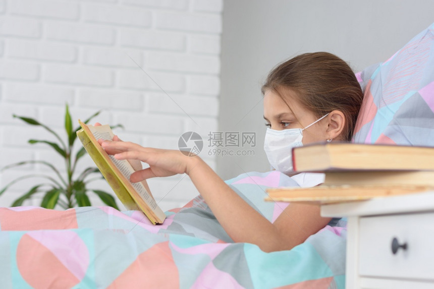 一个有流感的女孩正在读一本书床头柜上她面前专注于女孩图片