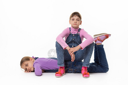 两名悲伤的女孩坐着休息躺在白背景上图片
