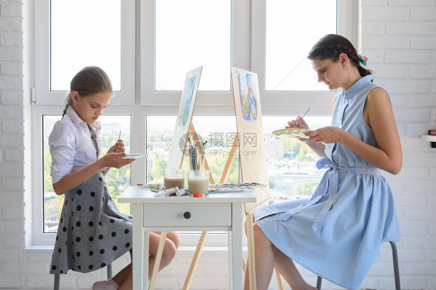 女孩和坐在家里的窗户旁边画图片
