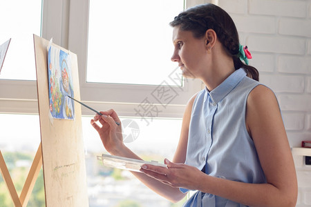 女孩坐在窗边的家门口用梳子和水彩画图片