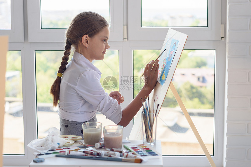 年轻艺术家在大窗户背景的斜坡上油漆水彩色图片