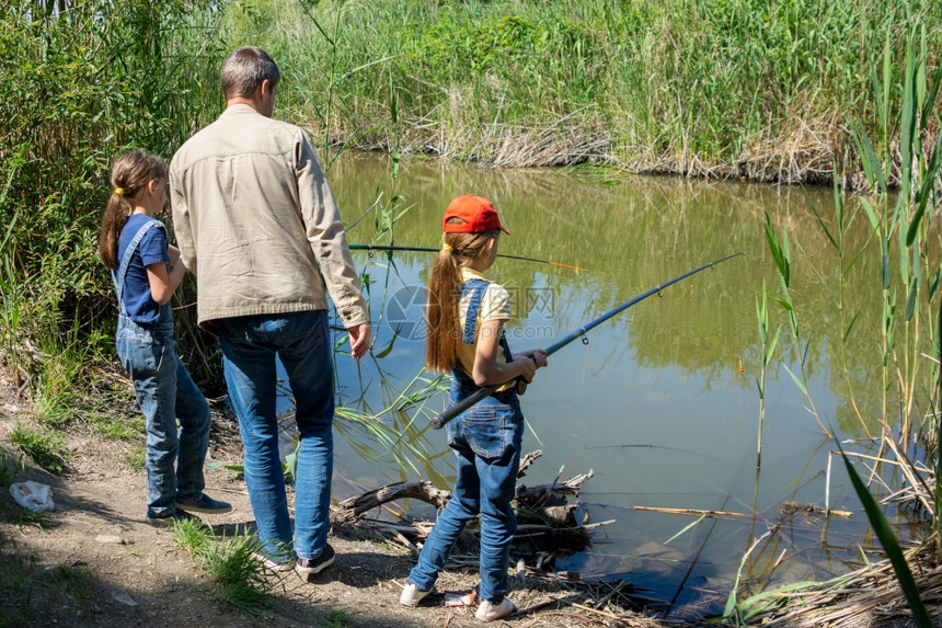 爸和两个女儿在湖边钓鱼图片