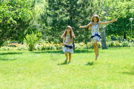 两个女孩在公园的绿草坪上跑来去玩得很开心图片