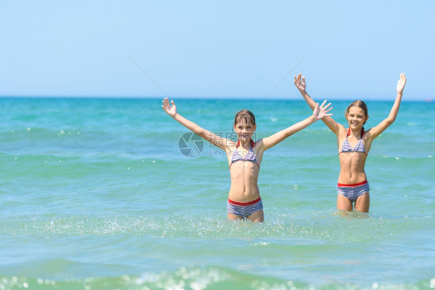 儿童站在海水中欢乐地举起手来图片