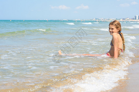 一个十岁的女孩坐在水里空海边图片