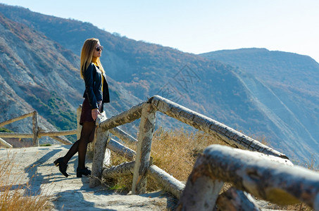 一个女孩在阳光温暖的天气中看着山上美丽的景色图片