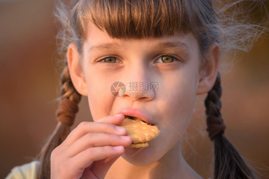 可爱的小女孩在日落时吃饼干特配图片