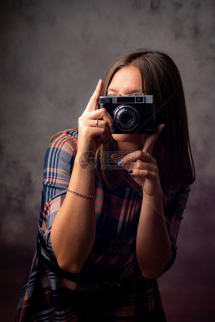 女摄影师拍照片时用反光相机半长的画室肖像在灰色背景上图片