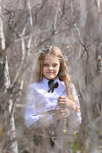 一个中世纪风格的女孩穿着中世纪风格的衣服拿着一把站在森林的灌木丛中图片