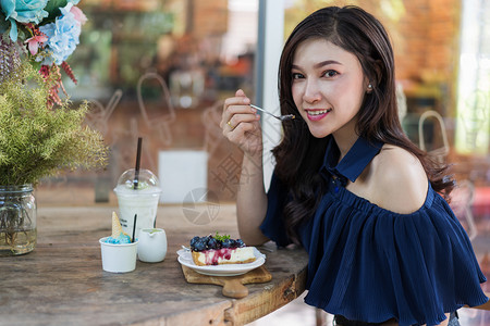 在咖啡馆吃蓝莓奶酪蛋糕的年轻女子图片