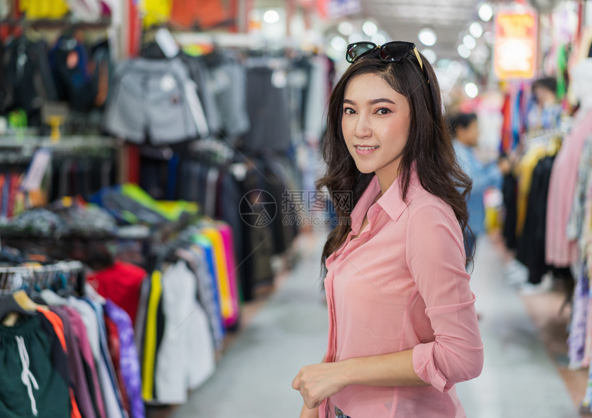 年轻妇女在购物商店选择和买服装图片