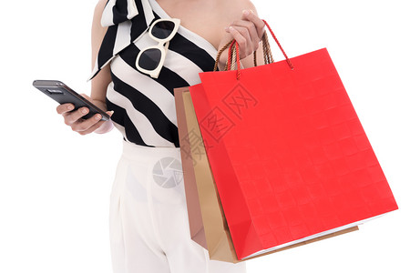 妇女使用智能手机和持有白种孤立的购物袋图片