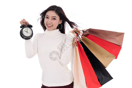 怀着购物袋和钟表的快乐妇女孤立于白色背景图片