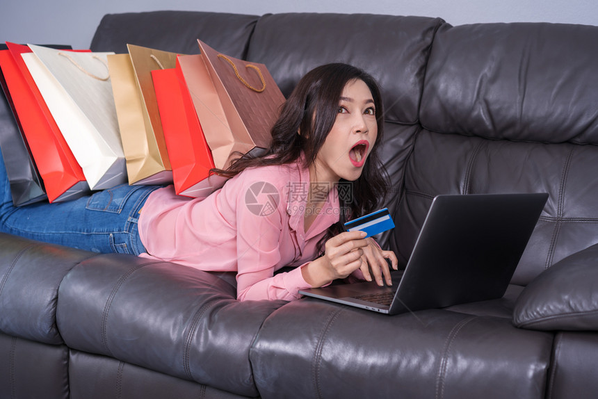 使用笔记本电脑在客厅用信卡线购物的震惊妇女图片