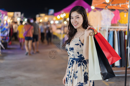 在户外夜市场买袋的幸福妇女图片
